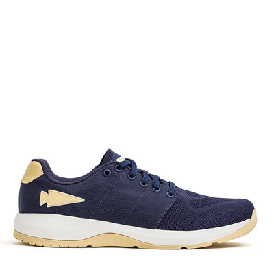 The Men’s Ballistic Trainers from GORUCK in Navy and White, accented with gold, are constructed with durable CORDURA® Ballistic Nylon. They feature a beige logo, white sole, dark laces, and gold reflective spearhead accents. Ideal for functional fitness enthusiasts who value reliable 3X Support.