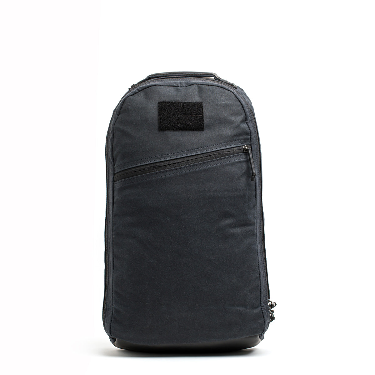 A sleek Bullet Ruck - Waxed Canvas backpack by GORUCK, with a minimalist design in dark gray, is showcased against a plain white background. It includes a front zip pocket and a small Velcro patch near the top.