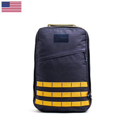 A black GR1 USA - Cordura backpack from GORUCK, showcasing yellow horizontal straps and a small American flag in the top corner, sits against a white background. Inspired by Special Forces gear, this original ruck embodies rugged durability and reflects the adventurous spirit of the GORUCK Challenge.