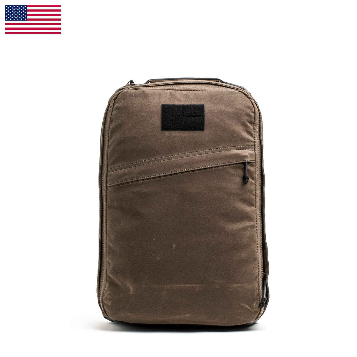 The GR1 USA - Heritage by GORUCK, a brown waxed duck canvas backpack featuring a zippered front pocket and a small black patch, is set against a plain white background. An American flag adorns the top left corner, adding character to this retro canvas rucksack.