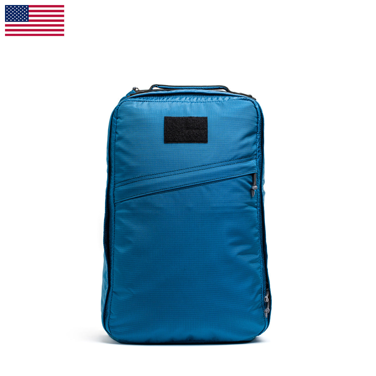 The GR1 USA - Ripstop ROBIC® backpack by GORUCK is an ultra-lightweight blue backpack made from Robic Ripstop Nylon, showcasing a black patch on the front. It is presented against a white background with a small U.S. flag in the corner, highlighting its water-resistant durability for everyday adventures.