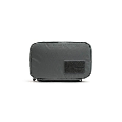 A gray rectangular travel organizer featuring a quilted pattern and a Velcro patch on the front, crafted from durable X-PAC material, this sleek accessory by GORUCK is compact and ideal for storing small items or electronics, resembling the style of the GR1 Field Pocket USA - X-PAC.