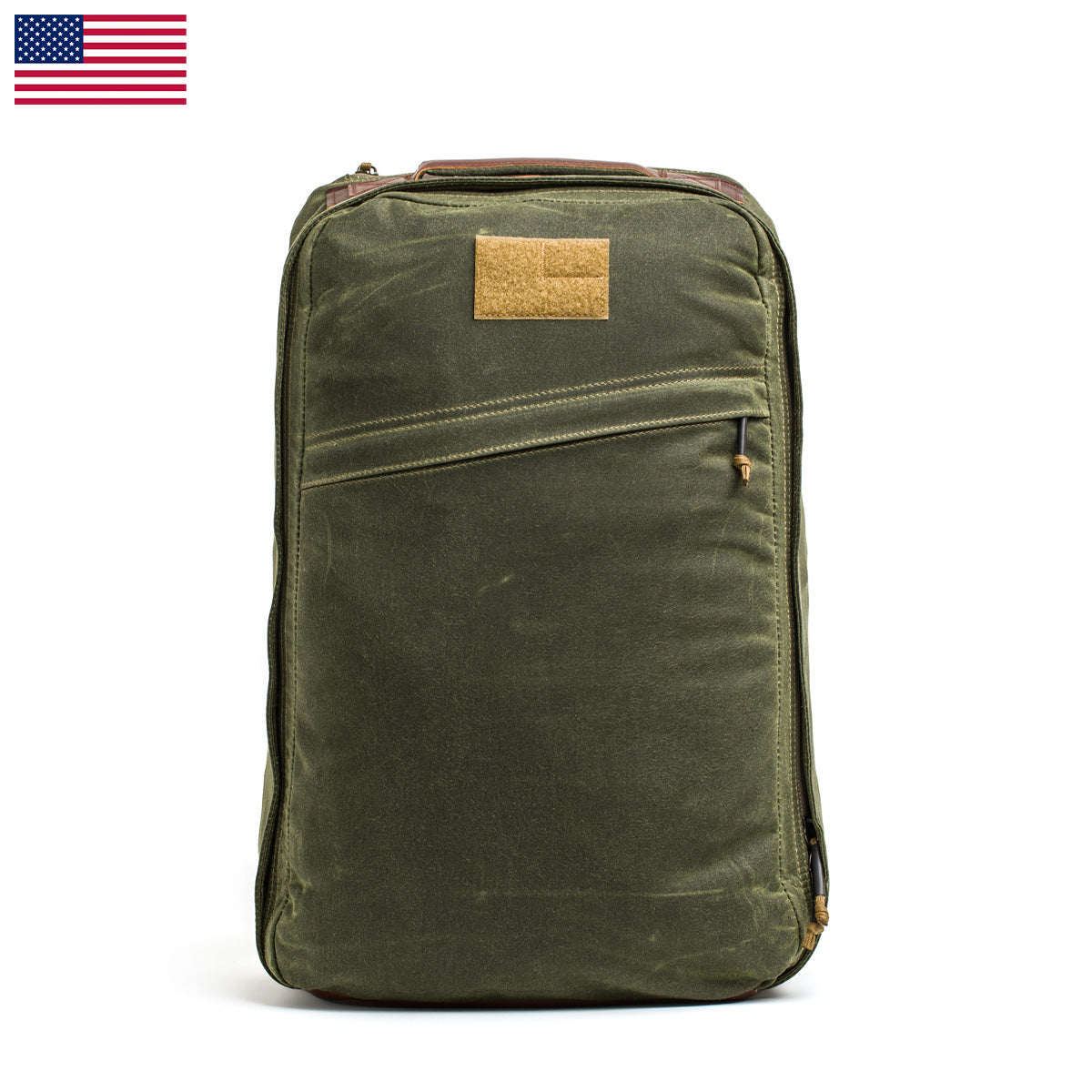 The GR1 USA - Heritage backpack by GORUCK is expertly crafted from waxed duck canvas, offering a rugged and sturdy appearance. It features a front zip pocket and a small patch, with weathered fabric detailing. An American flag is displayed in the top left corner, enhancing its design.