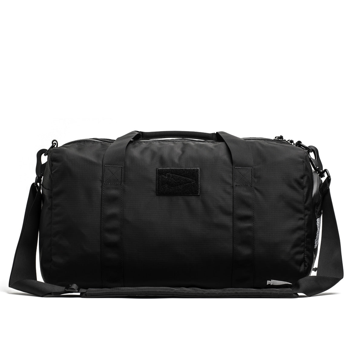 The Gym Bag - Ripstop ROBIC® by GORUCK is designed in black with durable ripstop nylon. It features robust handles and an adjustable shoulder strap, along with a minimalist design highlighted by a subtle rectangular patch on the front. With ample space and a dedicated shoe compartment, it is ideal for travel or gym use.