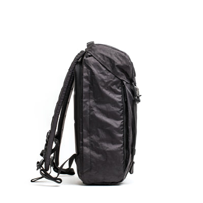 A side view of the M23 - Dyneema, a sleek and modern black rucksack by GORUCK, set against a white background. This bag is made from durable Dyneema® and boasts a minimalist design with padded shoulder straps and a top handle, reflecting the GORUCK standard.