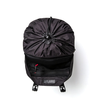 The GORUCK M23 - Dyneema is a stylish black backpack designed with an open top and visible inner compartments, complete with a mesh pocket and a distinctive small red strap. Crafted from durable Dyneema material, this contemporary rucksack is displayed laid flat on a white background.