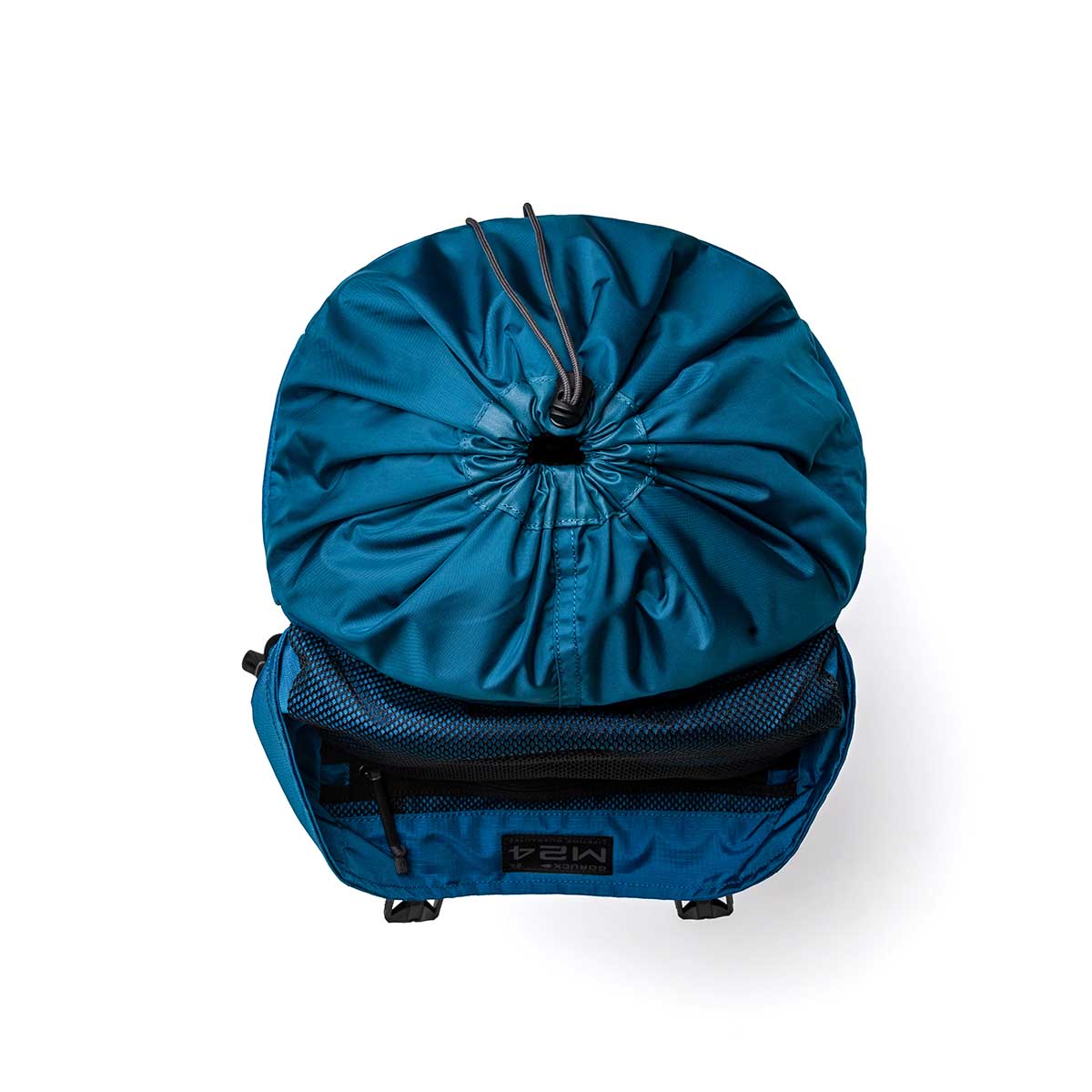 An overhead view of the GORUCK M24 - Ripstop ROBIC® drawstring backpack in blue, constructed from durable materials and equipped with a front zippered pocket for convenient access.