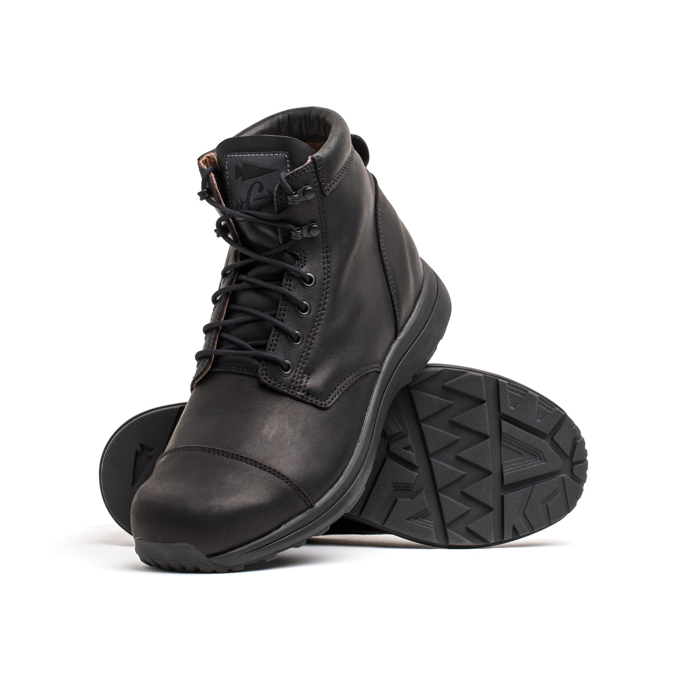 A pair of GORUCK MACV-1 Traveler x Carryology - Berserker Viking boots, one standing upright and the other tilted to showcase their rugged tread pattern. Made from water-resistant leather, these adventure boots sport laces and a smooth, matte finish, ideal for venturing into new terrains.