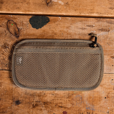 An Admin Panels pouch by GORUCK, featuring a brown zippered mesh design ideal for everyday carry, is displayed flat on a rustic wooden surface. Its woven texture and small zipper pull tab make it the perfect travel companion.