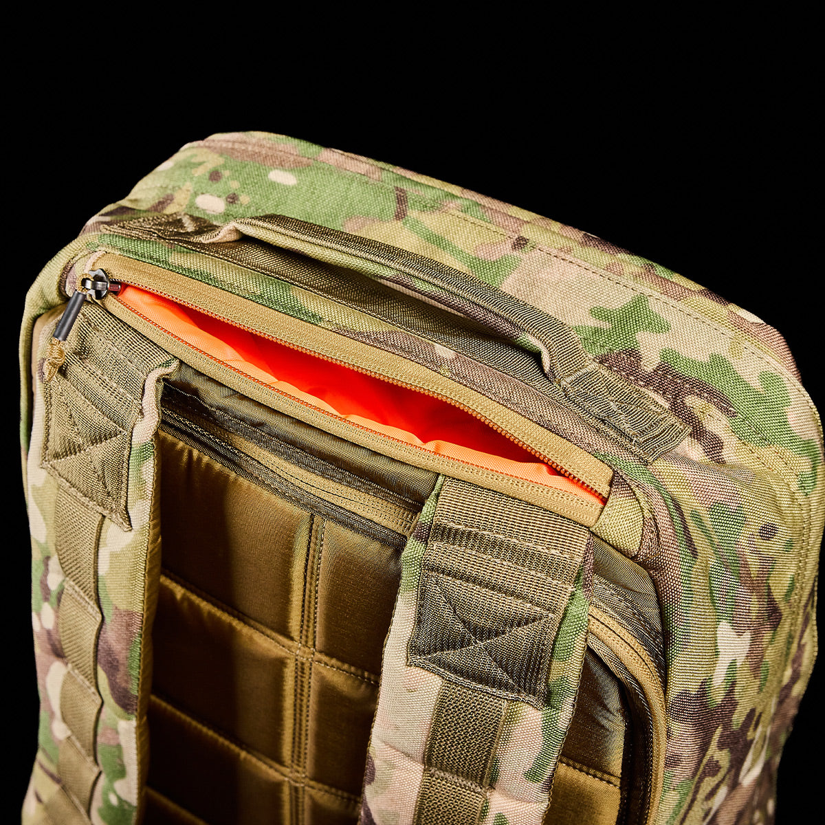 The Special Forces-tested GR1 USA - Cordura (The Original Ruck) backpack, with MOLLE webbing and an orange interior, is partially unzipped against a black background to reveal its bombproof laptop compartment.