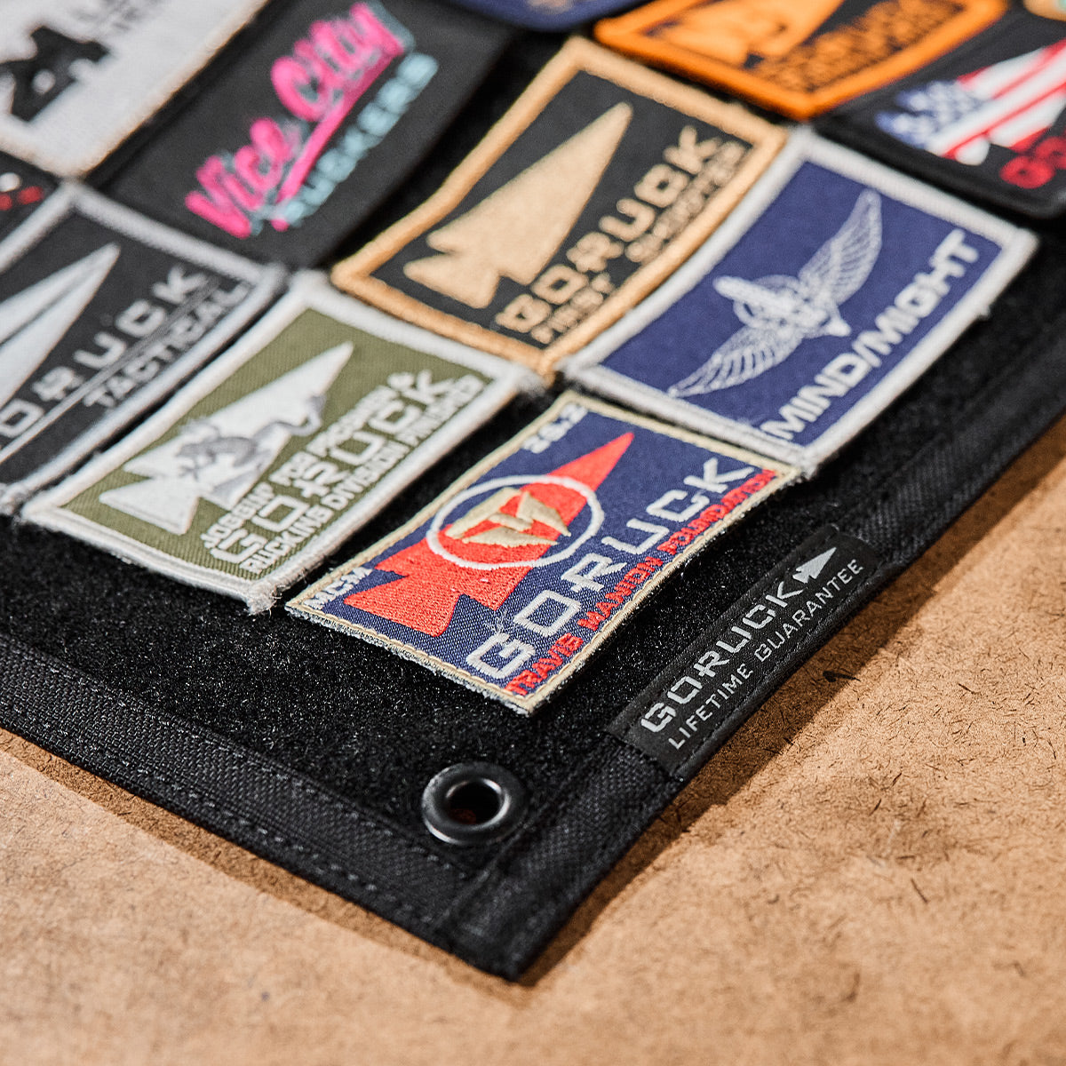 A robust 1000D Cordura surface, adorned with a lively array of colorful embroidered patches, mirrors the GORUCK Spearhead Patch Board by GORUCK.