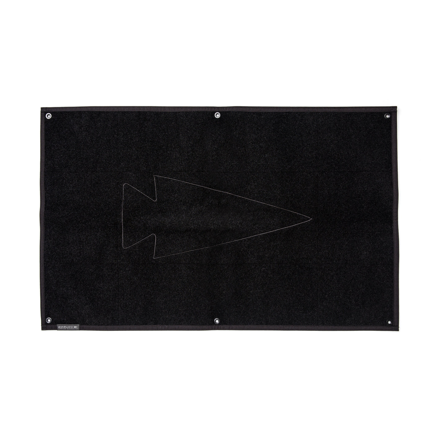 The black rectangular rug showcases a simple arrowhead design at its center, similar to the GORUCK Spearhead Patch Board, and is made with the robust 1000D Cordura material.