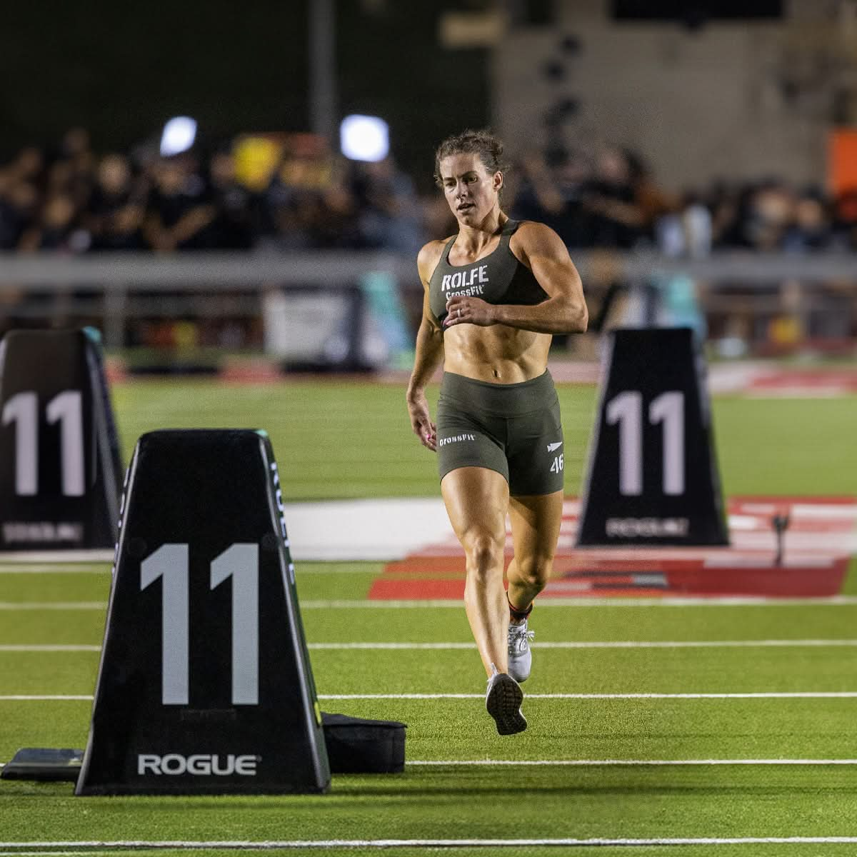 Wearing Race Day Socks, the athlete sprints on the track at night, enjoying maximum breathability with every stride while passing markers labeled "11".