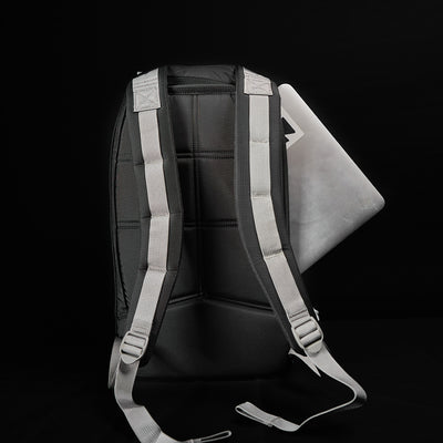 The GORUCK Bullet Ruck Laptop - Ripstop ROBIC® - 16L is displayed from the back against a dark background. Made from sturdy ROBIC® Ripstop Nylon, this black backpack with gray straps showcases a partially visible silver laptop in its open compartment, combining style with security.