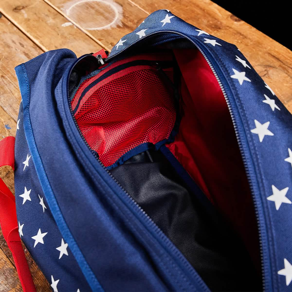 An open blue Kit Bag with white stars and a red interior, similar to an Aviator’s Kit Bag, rests on a wooden surface.