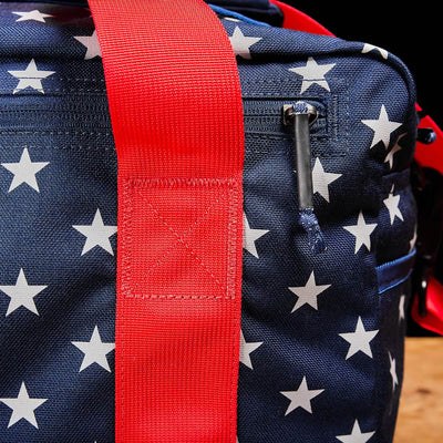 Close-up of the Kit Bag, featuring blue fabric with white stars and a thick red strap.