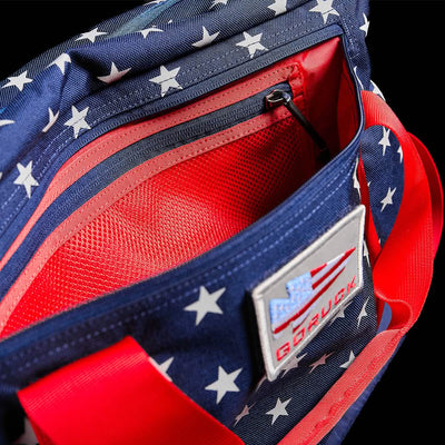 The Kit Bag, with its stars and bold red handles, invokes the spirit of an aviator's bag and includes a convenient interior pouch. Perfect for adventurers seeking a blend of style and patriotic flair, it also comes with a shoulder strap for added functionality.