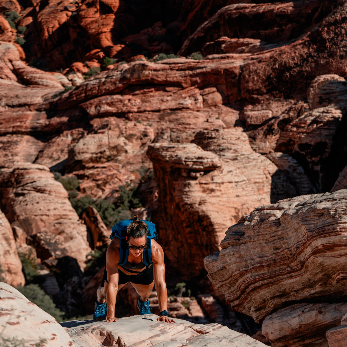 With a Rucker 4.0 from GORUCK, a person skillfully navigates the rocky terrain in a canyon, surrounded by striking red rock formations under the bright sunlight.