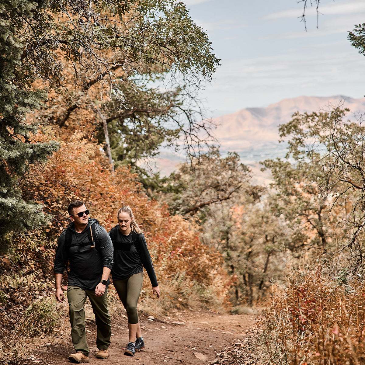 Man and woman rucking in mountains. Man is wearing Men's Sun Hoodie - ToughMesh in Charcoal