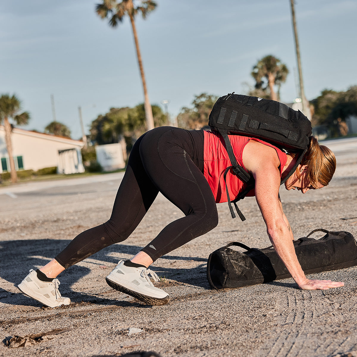 While participating in a Rough Runner challenge, a woman uses the Women's Rough Runner - Light Grey + Dark Grey backpack as she crawls outdoors on the rugged terrain.