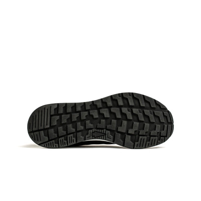 The image showcases the black sole of a Women's Rough Runner shoe by GORUCK, featuring a rugged tread pattern. Ideal for Special Forces missions, the design incorporates Gradient Density™ technology to boost performance. The sole is set against a plain white background.