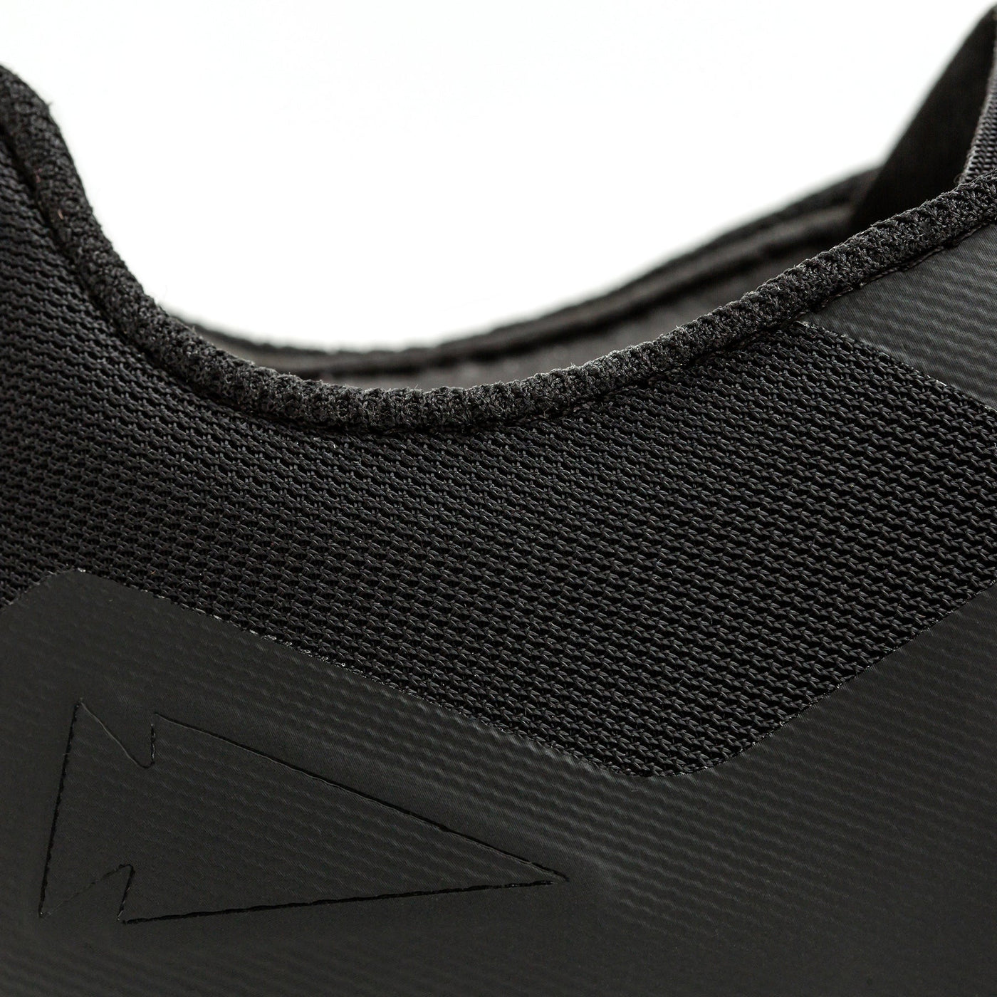 Close-up of the GORUCK Women's Rough Runner - Black + White shoe, highlighting the textured fabric and distinctive Rough Runner™ zigzag arrow pattern on the side. The image focuses on the upper part of the shoe, accentuating its material and design details crafted for Special Forces.