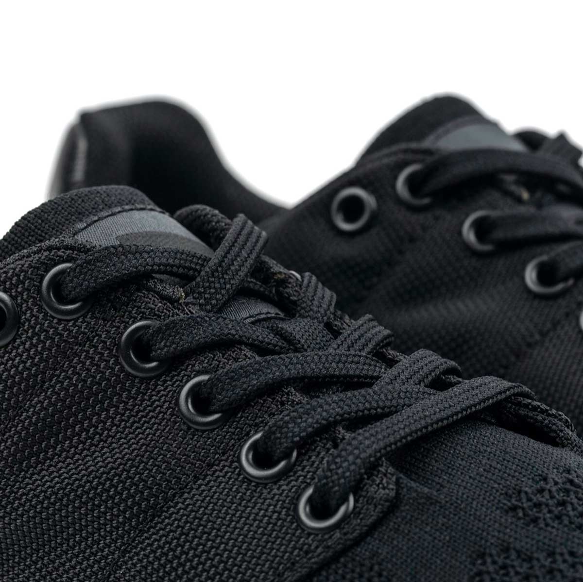 Close-up of Women's Ballistic Trainers - Blackout w/ Black Reflective Spearhead by GORUCK, crafted from durable black CORDURA® Ballistic Nylon with 3X Stability. The black laces and eyelets accentuate the fine texture and intricate stitching details, making them perfect functional fitness footwear.