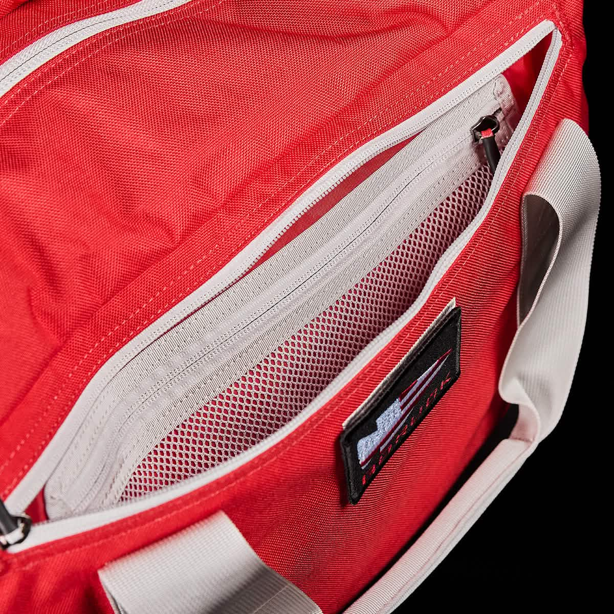 The Kit Bag, featuring a top zipper pocket and mesh interior, comes in red with white handles. Includes a shoulder strap, making it perfect for aviators on the go.