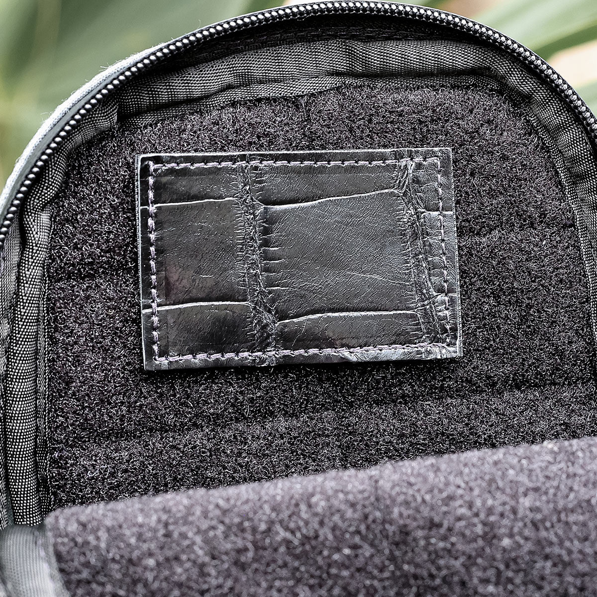 Close-up of a backpack's interior, featuring an Everglades Mystery Leather Patch by GORUCK stitched onto a textured fabric backing. The patch, framed by a zipper lining, emphasizes the contrast between the fabric's texture and the smoothness of this unique leather piece.