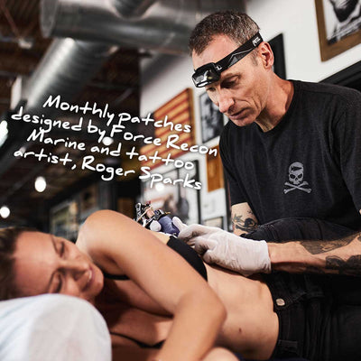 A tattoo artist captures dedication on a woman's side, reflecting the spirit of Roger Sparks' monthly patches and the grit of GORUCK Tribe's sandbag workouts in "Tribe 'n Training.