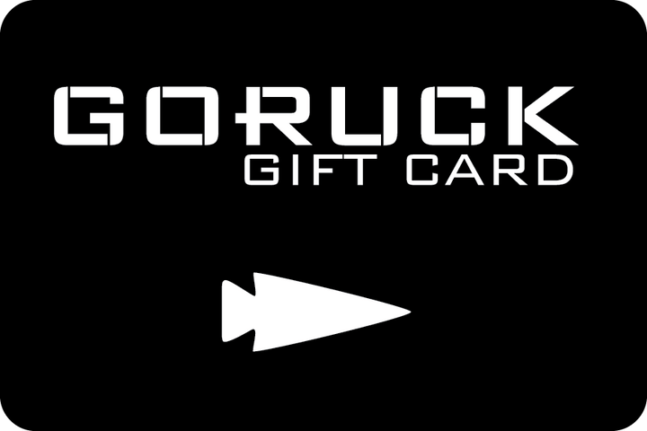 A sleek black GORUCK e-Gift Card with white text displaying "GORUCK Gift Card" and a distinctive white arrowhead symbol at the bottom, ideal for your next gear purchase.