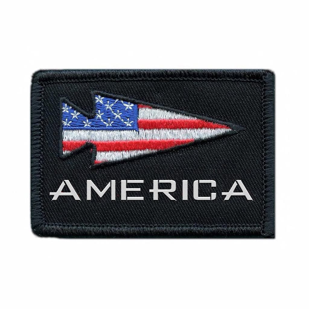 The Patch - GORUCK America by GORUCK-DEMO is a black embroidered patch measuring 2" x 3". It features the word "AMERICA" in white under a stylized arrowhead decorated with stars and stripes from the American flag. A VELCRO® backing ensures easy attachment.