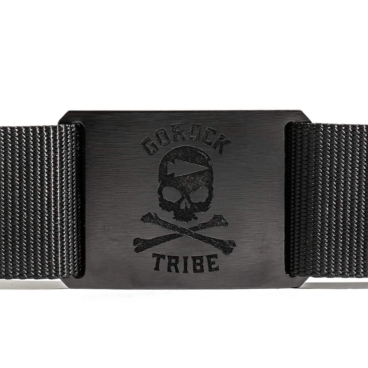 The Tribe Tactical Belt by Grip 6 is a stylish, USA-made black belt featuring a decorative skull and crossbones on a metal buckle with the text "GORUCK TRIBE," offering both style and reliability.